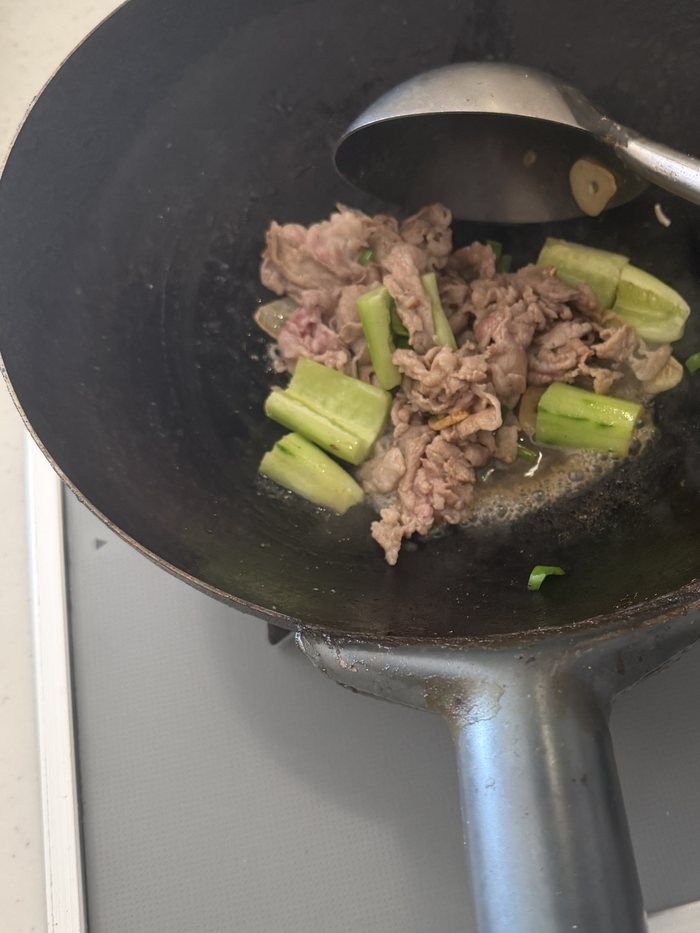 鉄の中華鍋で野菜と肉を炒めているところ